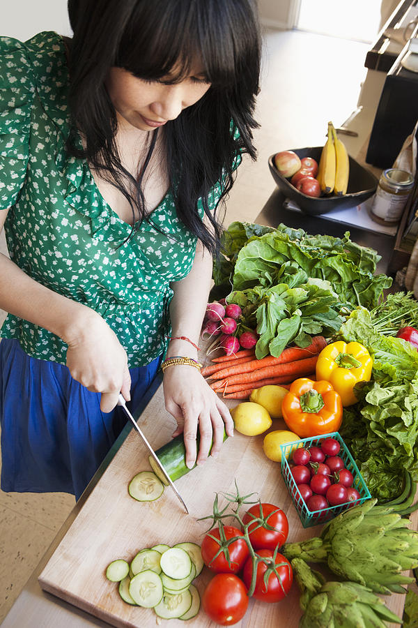 Woman chopping vegetables in kitchen Photograph by Lucy von Held