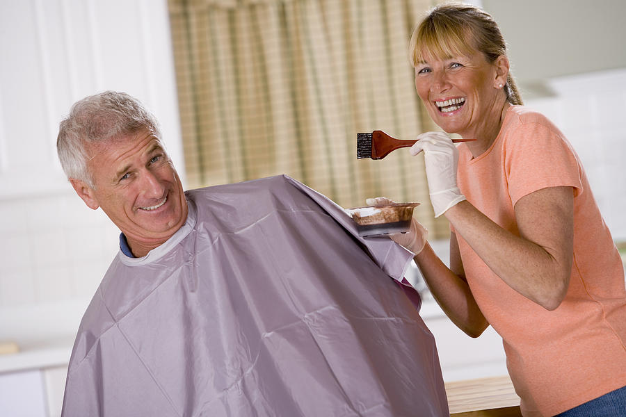 Woman coloring a mans hair Photograph by Comstock Images