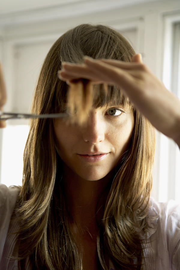 Woman cutting hair with scissors, close-up Photograph by Simon Lekias