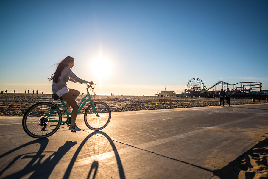 Woman cycling on Santa Monica beach, CA, USA Photograph by Anna Bryukhanova