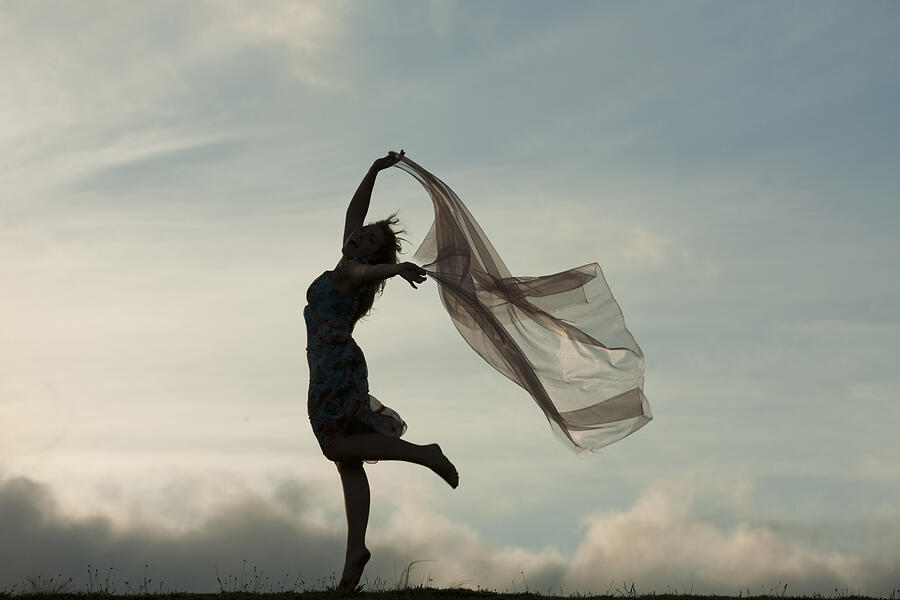 Woman dancing with sheer fabric over head Photograph by Zero Creatives