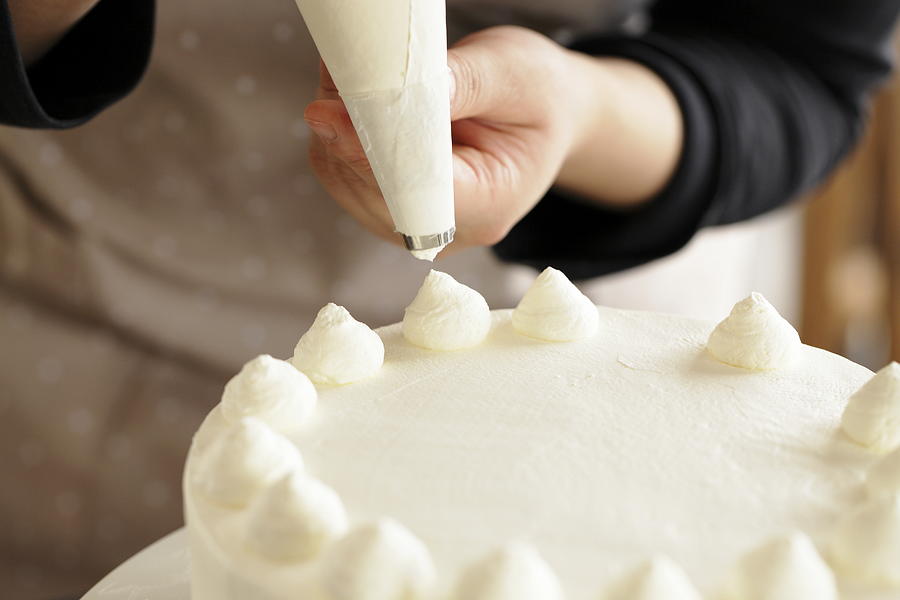 Woman decorating whipped cream on cake Photograph by Sot