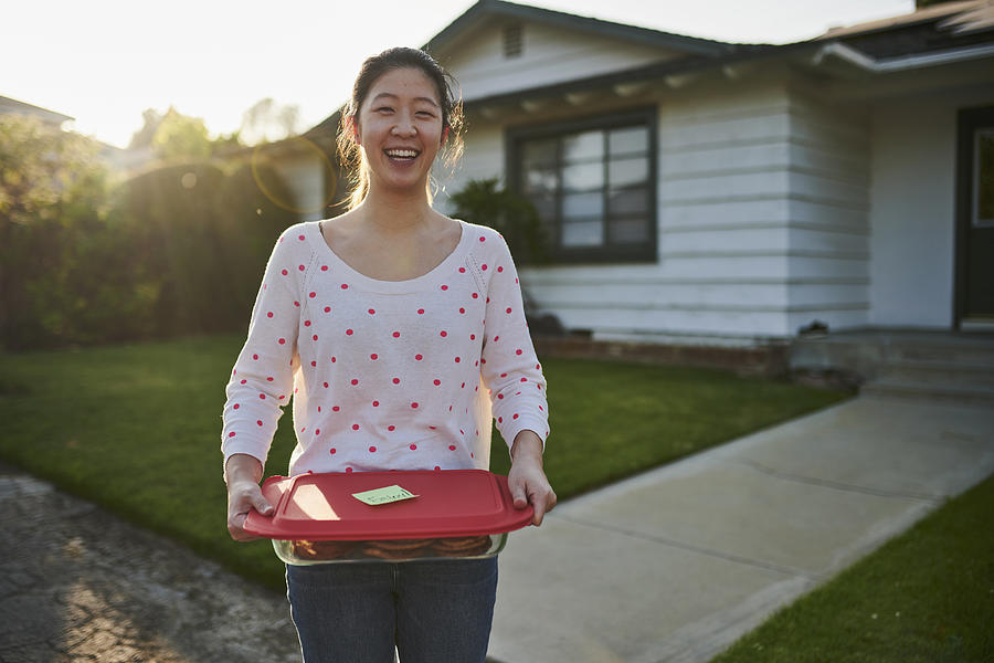 Woman delivering homemade cookies to neighbor Photograph by The Good Brigade