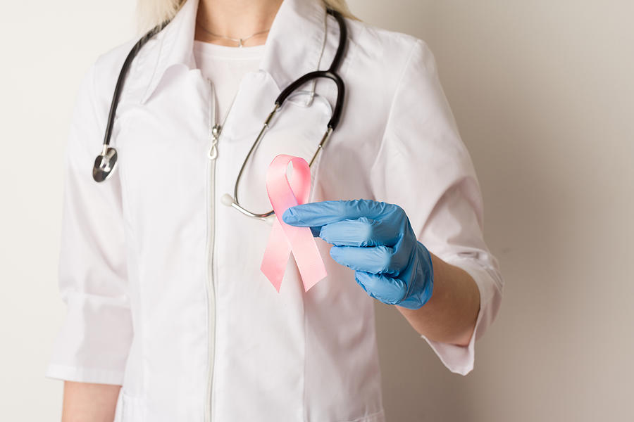 Woman doctor holding a pink ribbon in her hands Photograph by Unomat