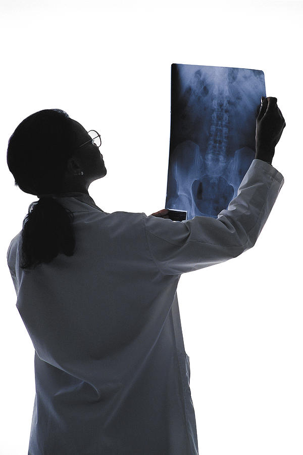 Woman doctor reading x-ray Photograph by Comstock