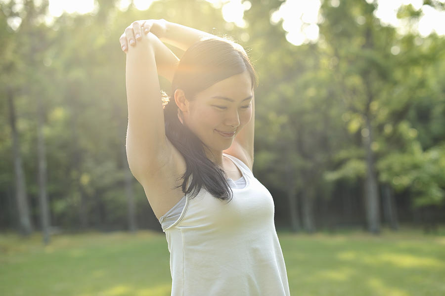 Woman doing stretch exercises in nature Photograph by Yagi Studio