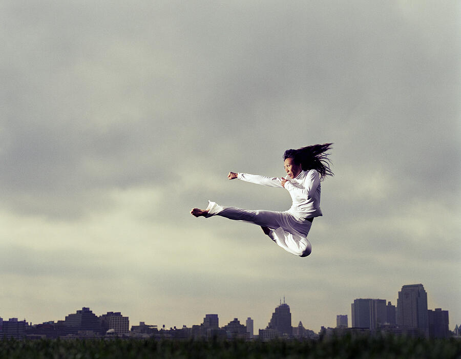 Woman doing tae kwon do kick in park, low angle view Photograph by PM Images