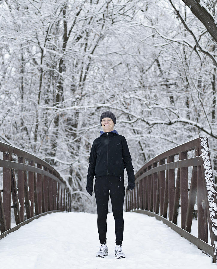 Woman dressed for winter running on snowy bridge Photograph by Tony Anderson