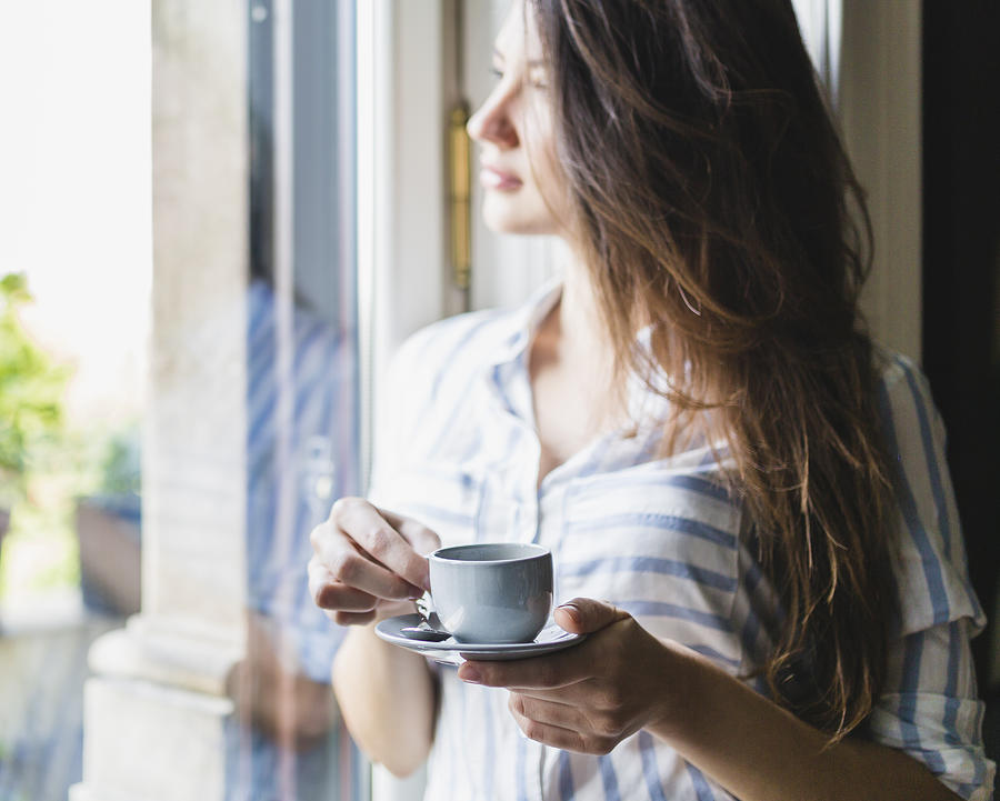 Woman drinks coffee at home Photograph by Deimagine