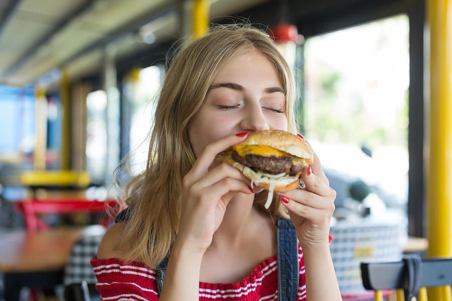 Woman eating a hamburger Photograph by Bymuratdeniz