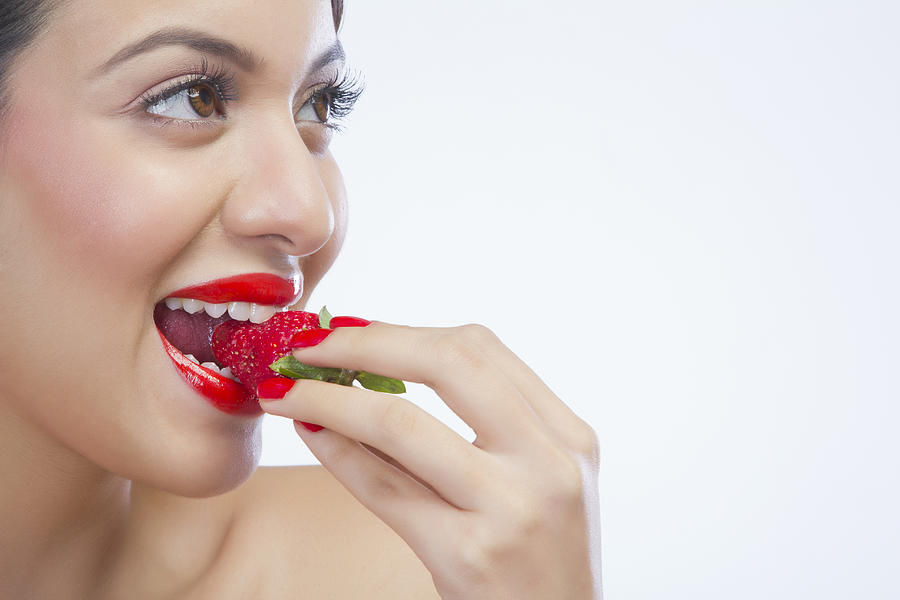 Woman eating a strawberry Photograph by IndiaPix/IndiaPicture