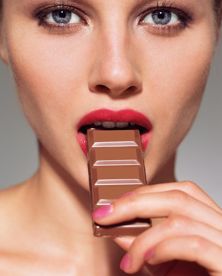 Woman eating bar of chocolate Photograph by Image Source