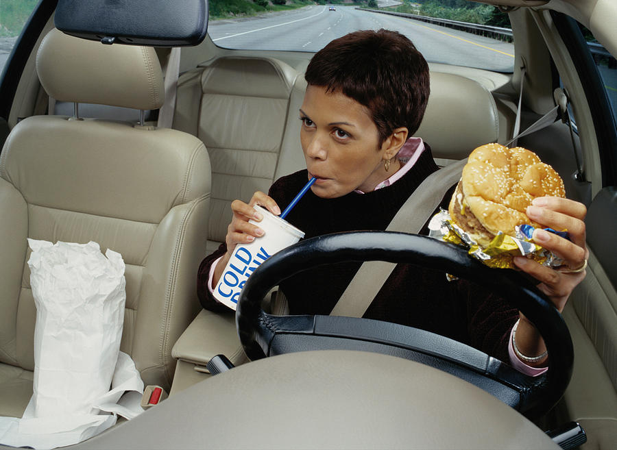 Woman Eating Fast Food While Driving Photograph by Ryan McVay