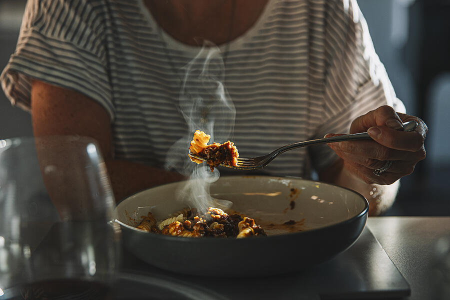Woman eating fusilli pasta with bolognese sauce Photograph by Justin Paget