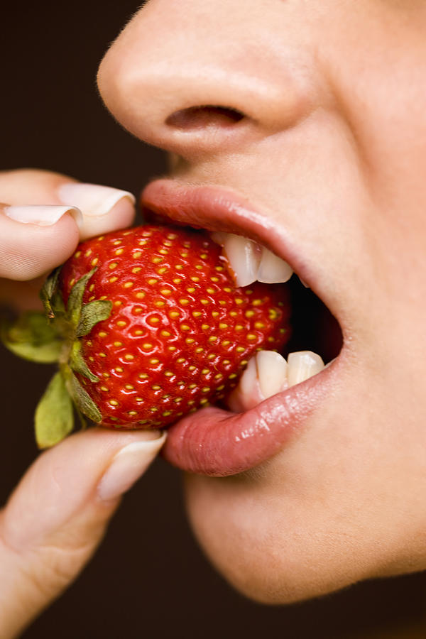 Woman eating strawberry, close up, side view Photograph by Sean De Burca