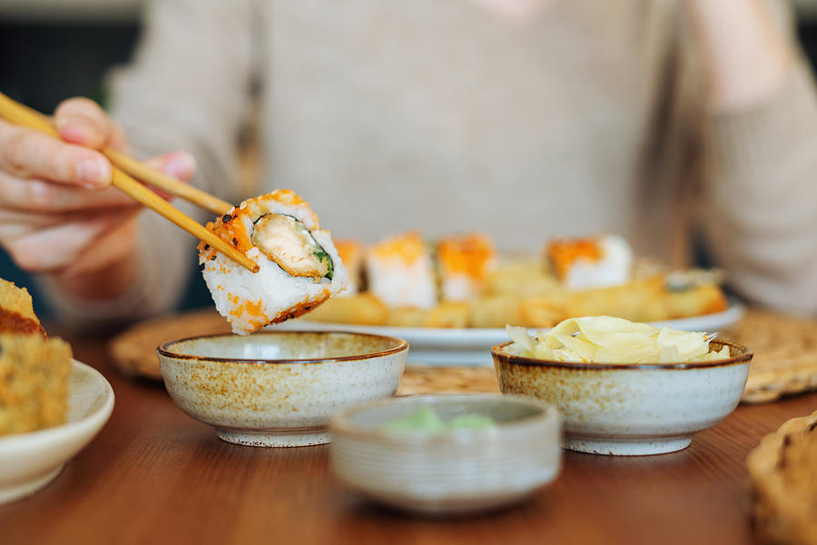 Woman eating sushi rolls Photograph by Xsandra