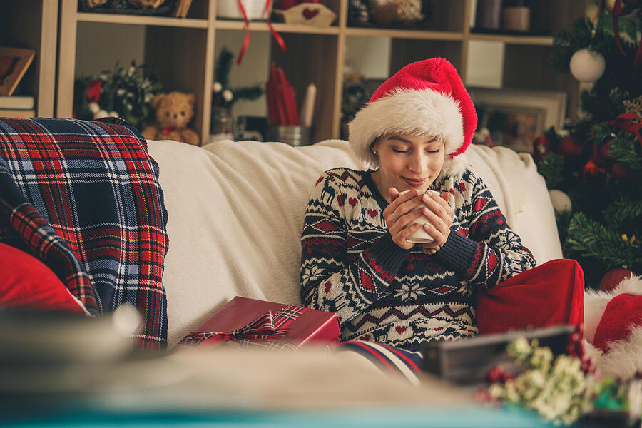 Woman enjoying hot tea on a sofa during Christmas time Photograph by Fotostorm
