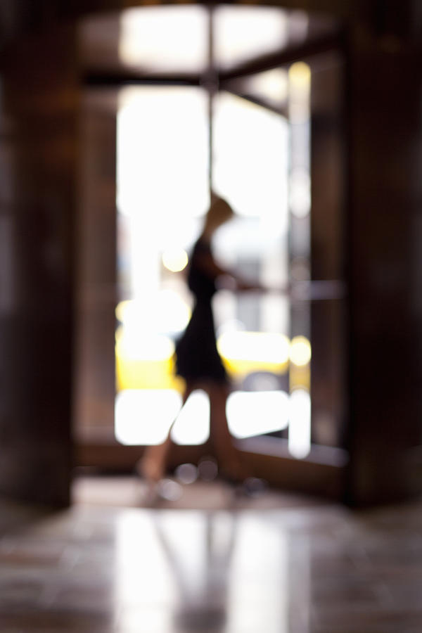 Woman entering revolving door, blur Photograph by Assembly