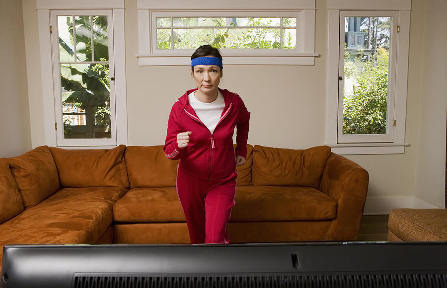 Woman exercising in front of television Photograph by Sean Murphy