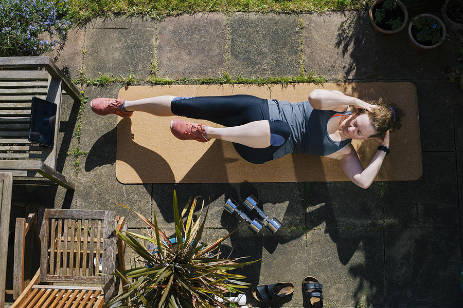 Woman exercising in her garden Photograph by Gary Yeowell
