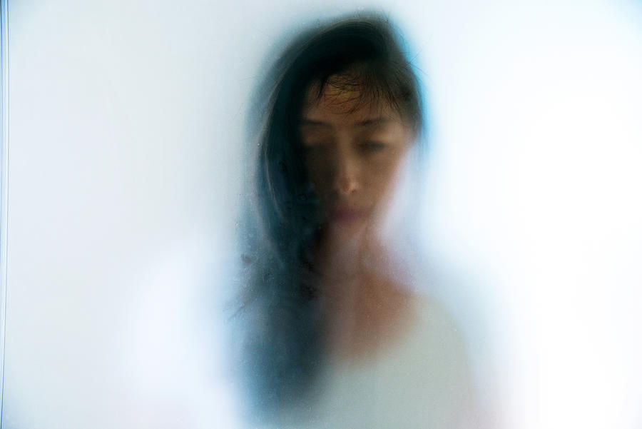 Woman face peering through frosted glass Photograph by Baona
