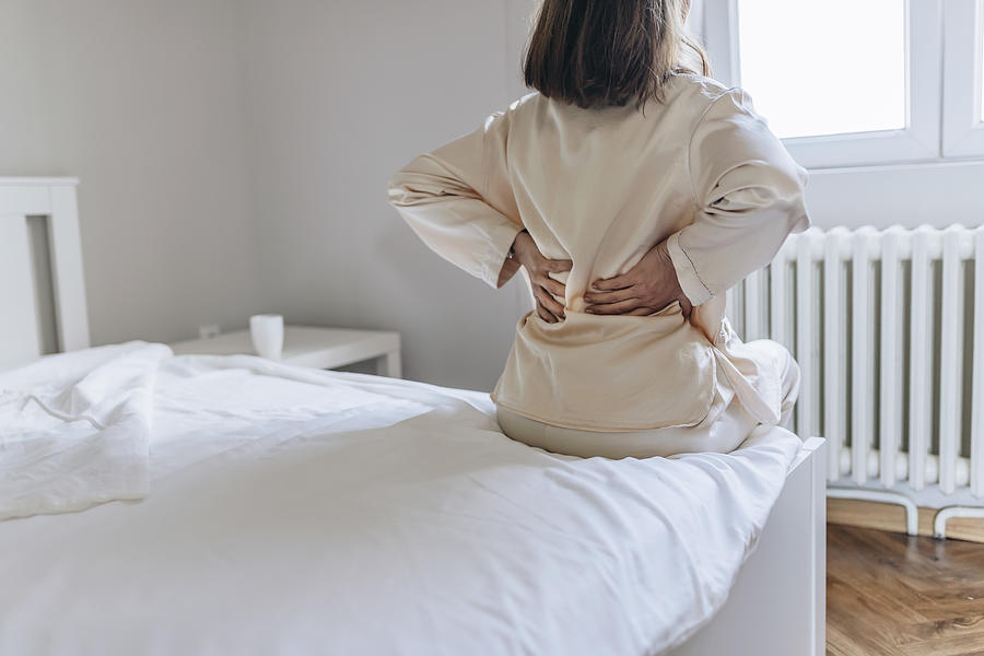 Woman feels back pain massaging aching muscles Photograph by PixelsEffect