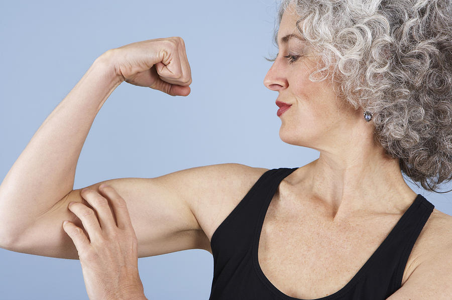 Woman flexing bicep Photograph by Jupiterimages