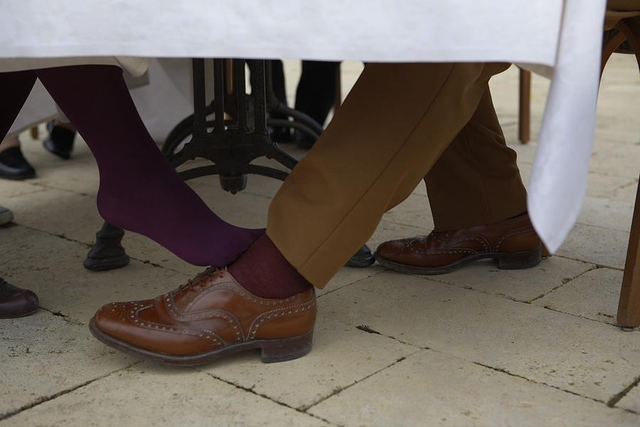 Woman flirting with man under table Photograph by Tim Macpherson