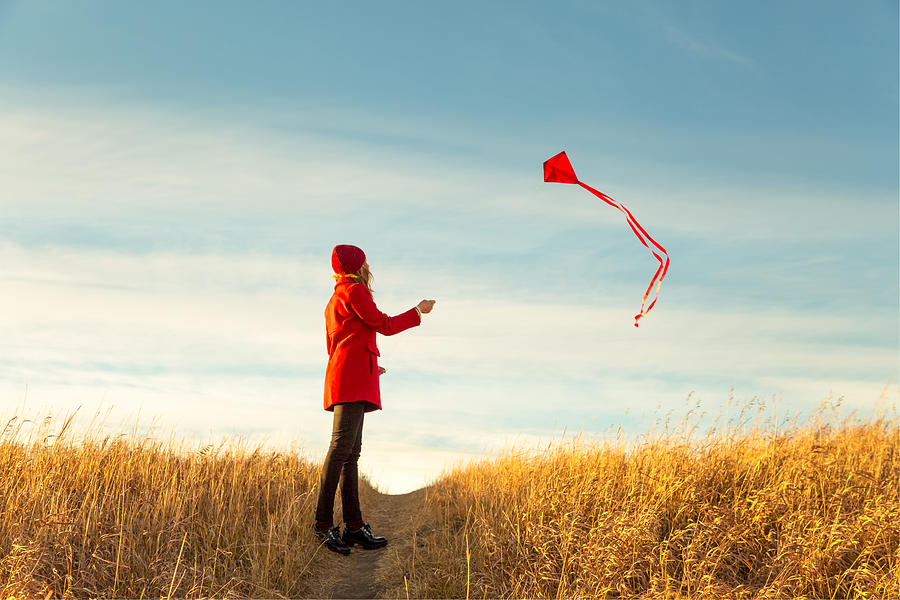 Woman flying kite in prairies Photograph by Lori Andrews