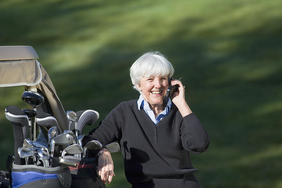 Woman golfer on cell phone Photograph by Comstock Images