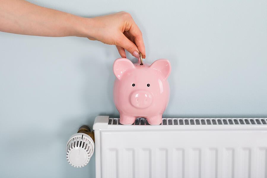 Woman Hand Inserting Coin In Piggybank On Radiator Photograph by AndreyPopov