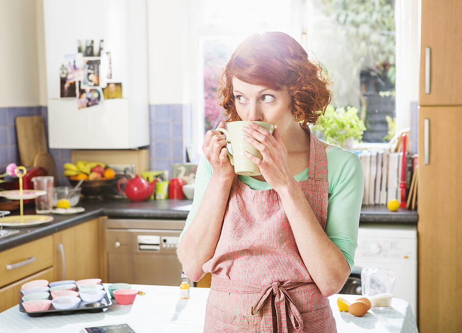 Woman having a cup of tea while baking cupcakes. Photograph by Betsie Van Der Meer