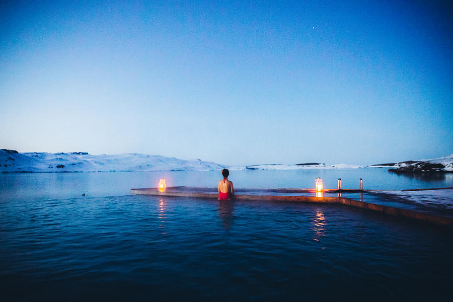 Woman having bath in thermal pool with view of the snowy mountains and frozen lake in Iceland Photograph by Anastasiia Shavshyna