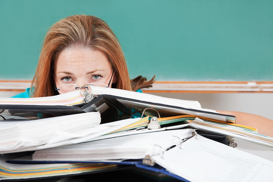 Woman hiding behind school binders in classroom Photograph by SDI Productions