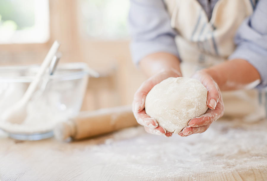 Woman holding ball of dough in kitchen Photograph by Tom Merton