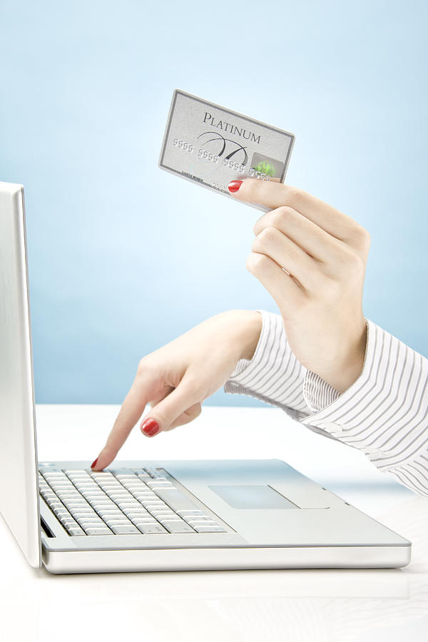 Woman holding credit card and using laptop Photograph by Tooga