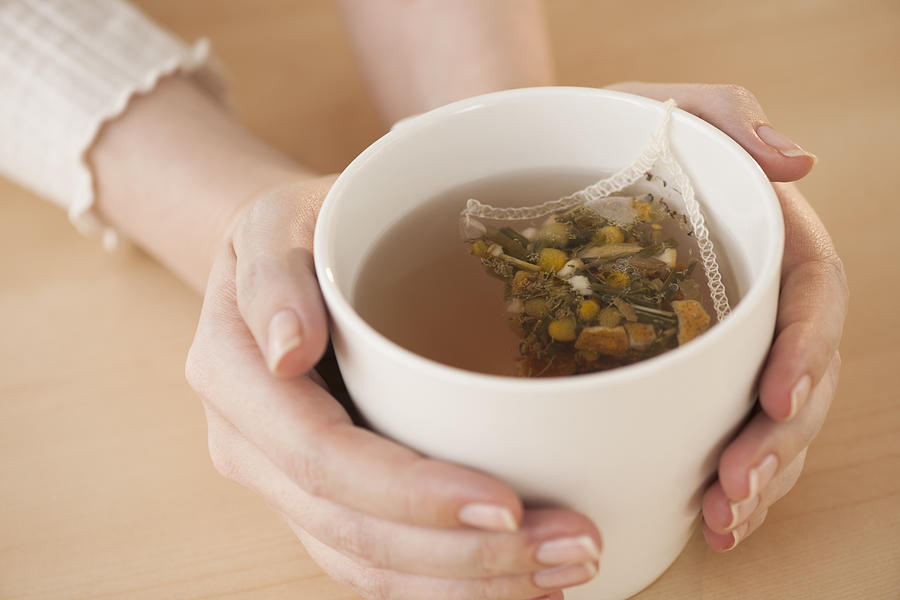 Woman holding cup with chamomile tea Photograph by Tetra Images