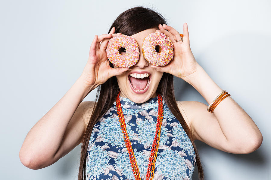 Woman holding doughnuts in front of eyes. Photograph by Betsie Van Der Meer