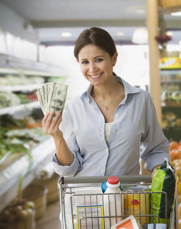Woman holding money and shopping in grocery store Photograph by Jose Luis Pelaez Inc