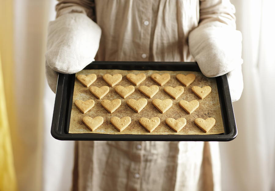 Woman holding oven tray of heart cookies Photograph by Sot