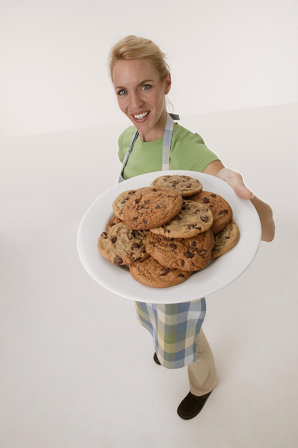 Woman holding plate of cookies Photograph by Comstock Images