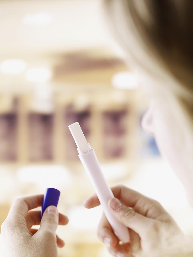 Woman holding pregnancy test Photograph by Chris Ryan