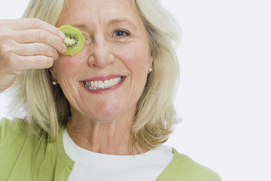 Woman holding slice of kiwi Photograph by Image Source