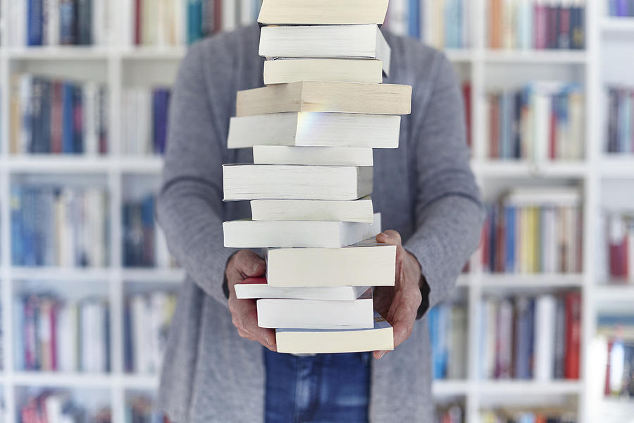Woman holding stack of books, mid section Photograph by Maria Fuchs