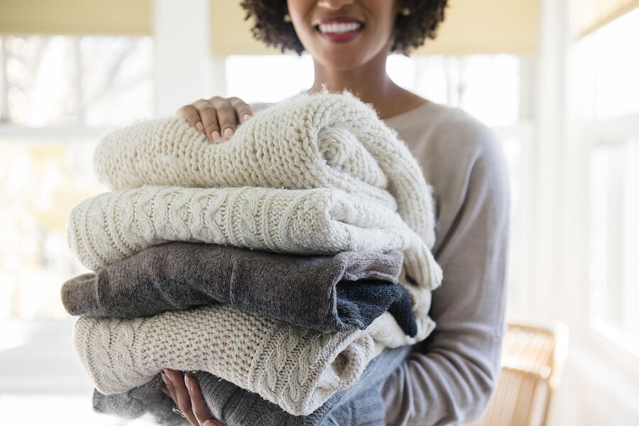 Woman holding stack of folded sweaters Photograph by Tetra Images