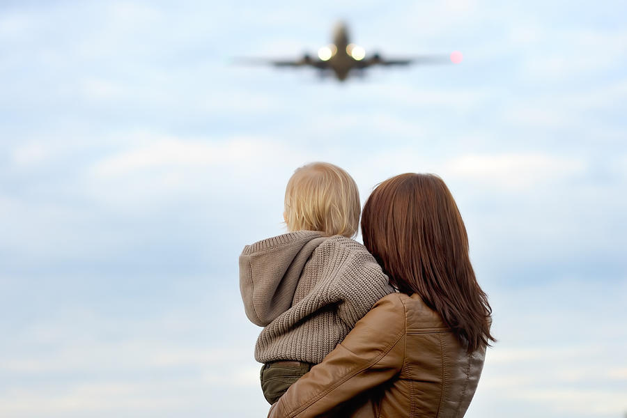 Woman holding toddler with airplane on background Photograph by SbytovaMN
