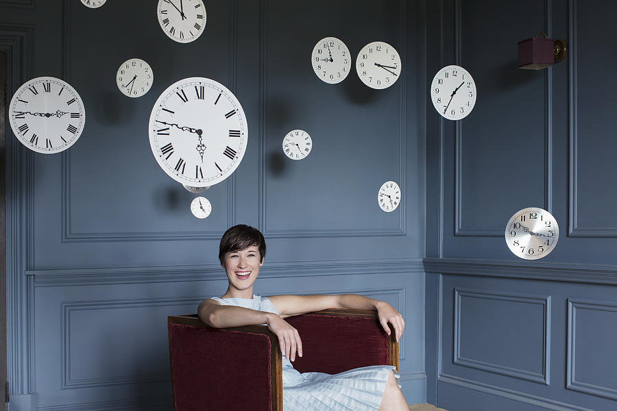 Woman in armchair with hanging clocks above Photograph by Anthony Harvie