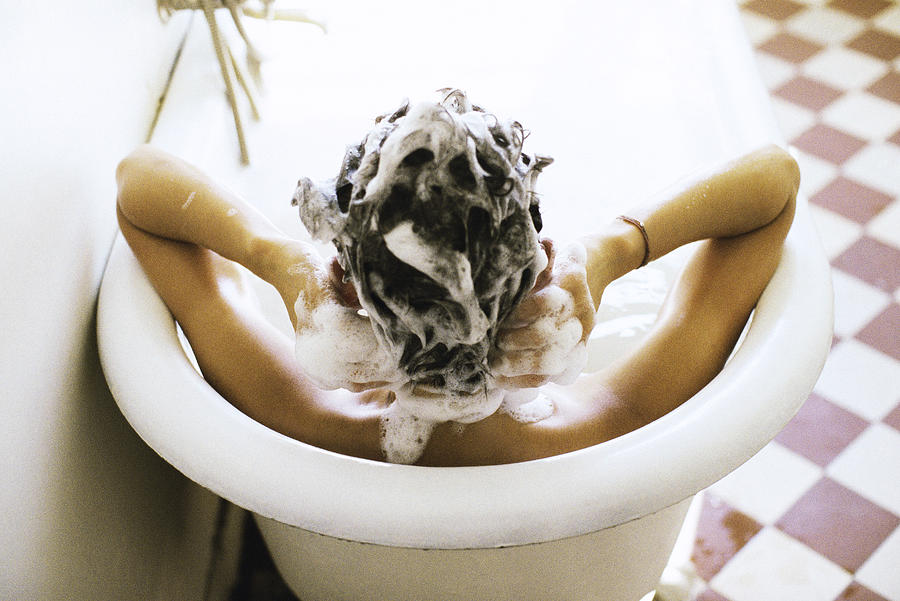 Woman in bath shampooing hair Photograph by PhotoAlto/John Dowland