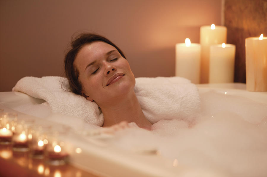 Woman in bubble bath with candles Photograph by Comstock