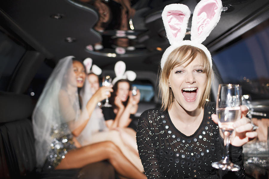 Woman in bunny ears drinking champagne in limo Photograph by Tom Merton